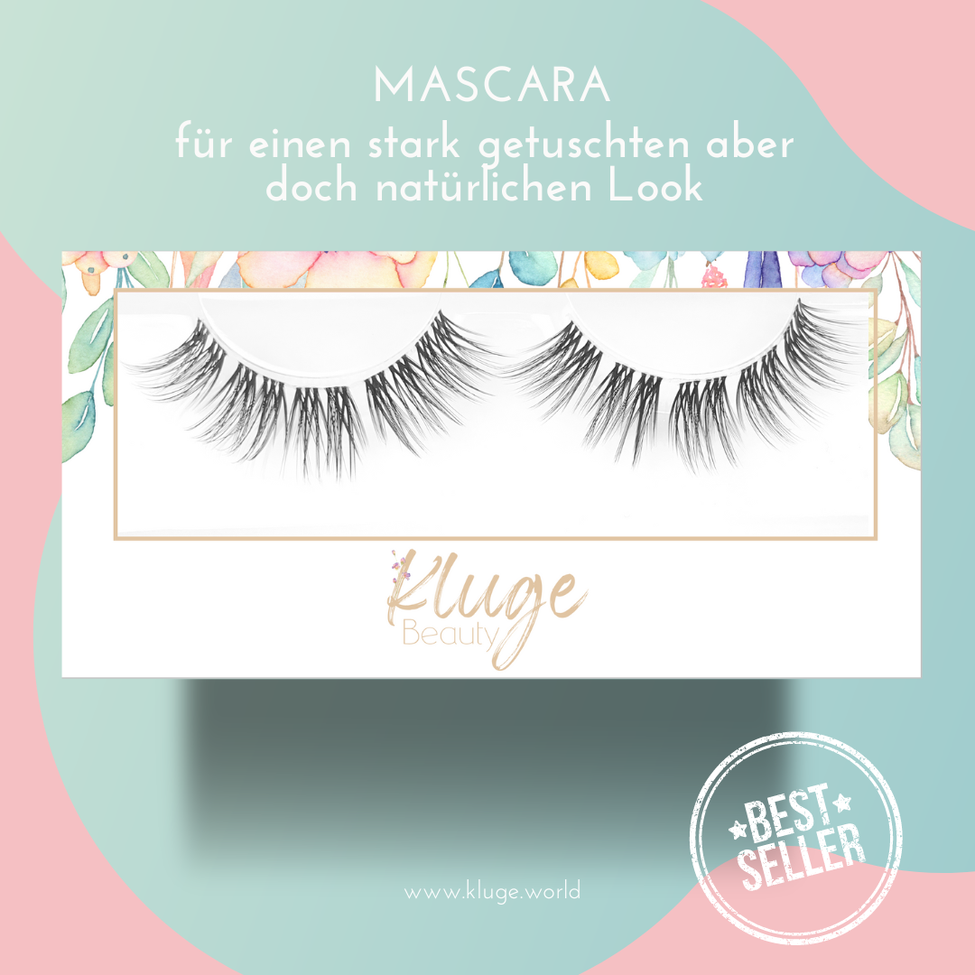 Nahaufnahme einer luxuriösen Wimpernbox mit "Mascara" für einen intensiven, dennoch natürlichen Look, präsentiert auf einem stilvollen pastellfarbenen Hintergrund.