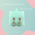 Mint Heart Short Ohrringe aus der Schmuckkollektion von Kluge Beauty. Elegante goldene Ohrringe mit roten Herz-Details, funkelnden Zirkonia und mintfarbenen Steinen. Präsentiert auf einer mintgrünen Schmuckverpackung vor einem pastellfarbenen Hintergrund mit rosa und blauen Akzenten. Ideal für einen stilvollen und luxuriösen Look.