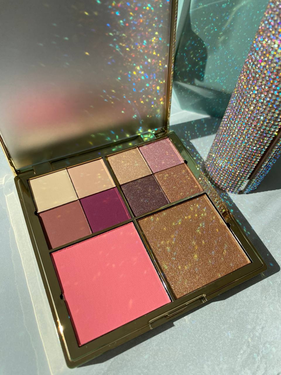 Offene Lidschattenpalette von Kluge Beauty mit schimmernden goldenen und rosa Farbtönen sowie Rouge.