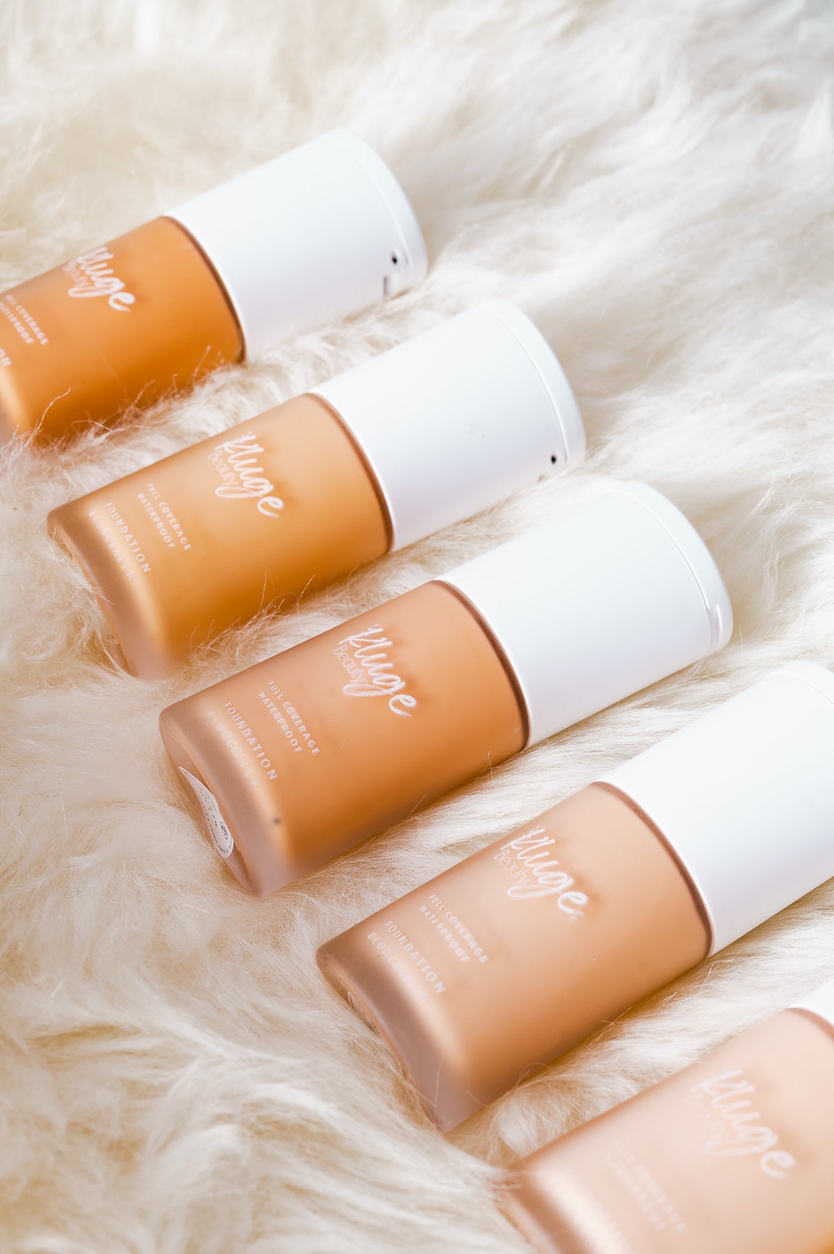 Nahaufnahme der Kluge Beauty Foundation-Flakons, schräg arrangiert auf weichem Fell für eine hochwertige Präsentation.