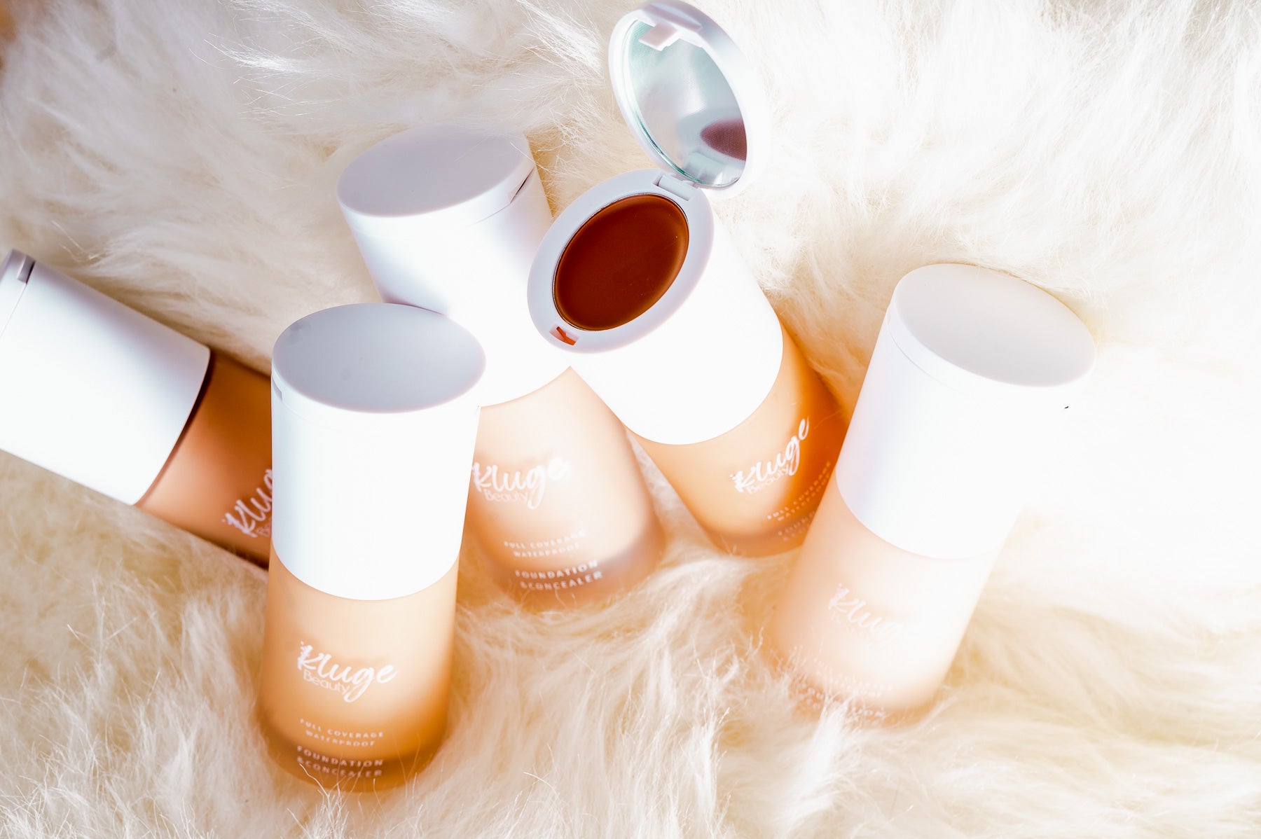 Kluge Beauty Foundation mit offenem Deckel, die cremige Konsistenz und luxuriöse Verpackung hervorhebend. Präsentiert auf stilvollem Fellhintergrund.