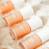 Kluge Beauty Foundation-Flakons in einer Reihe auf weichem, cremefarbenem Fell präsentiert. Die Flaschen zeigen eine luxuriöse Verpackung mit minimalistischen weißen Kappen.